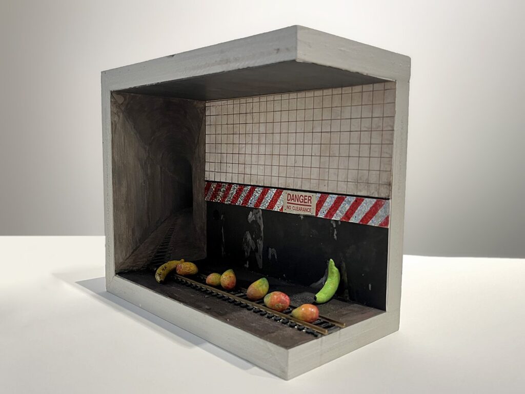 DANGER– No Clearance, by Audrey Rodriguez, 2023, clay, styrene, acrylic, epoxy, model train tracks, gouache, paper, and wood